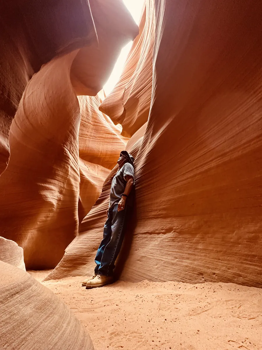 A guest resting against the curved wall of Lower Antelope Canyon