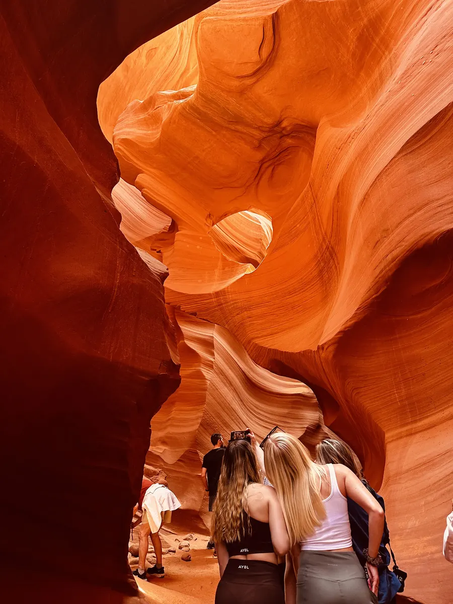 Guests walking between glowing walls in Lower Antelope Canyon