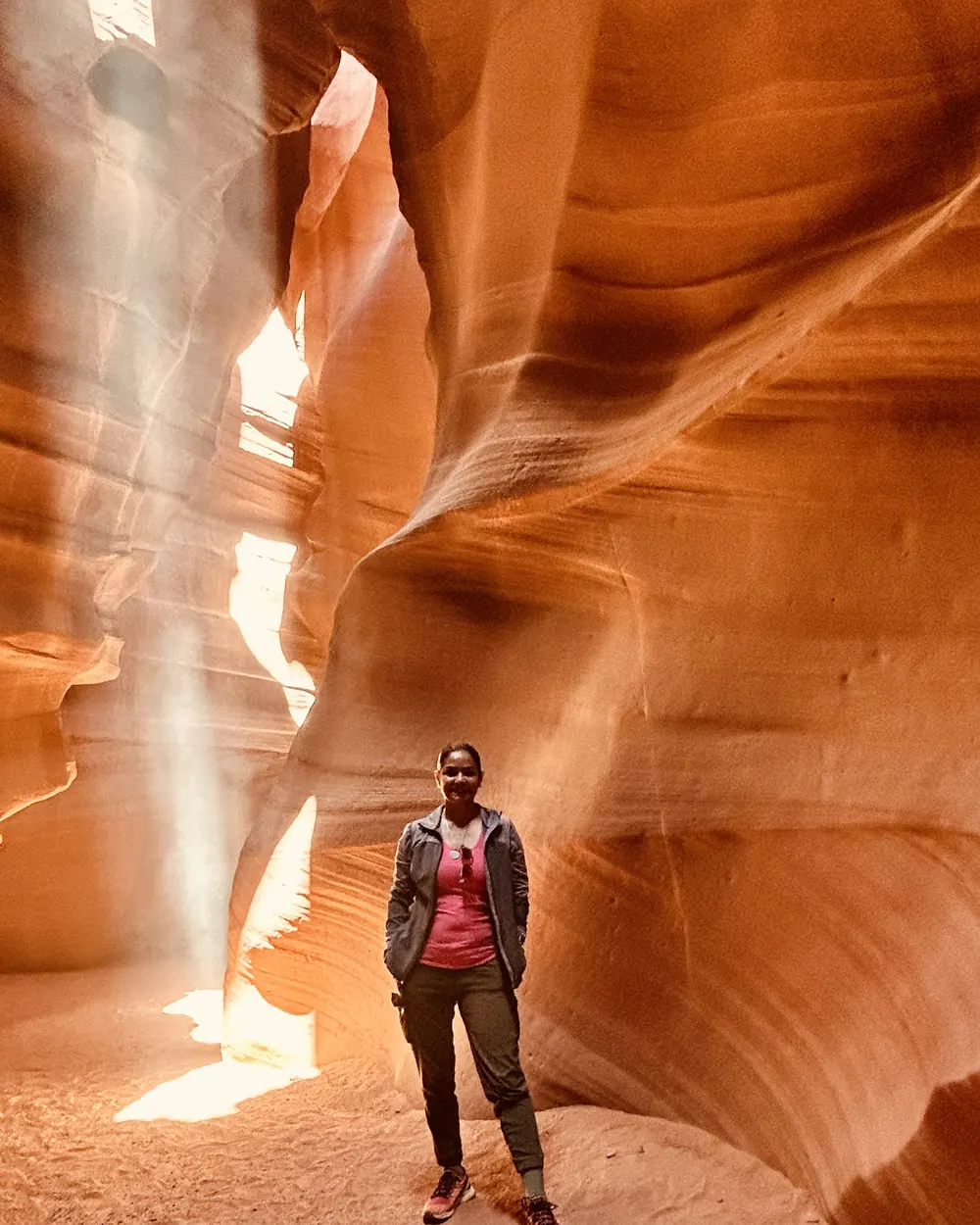 A guest standing in a beam of light inside Upper Antelope Canyon