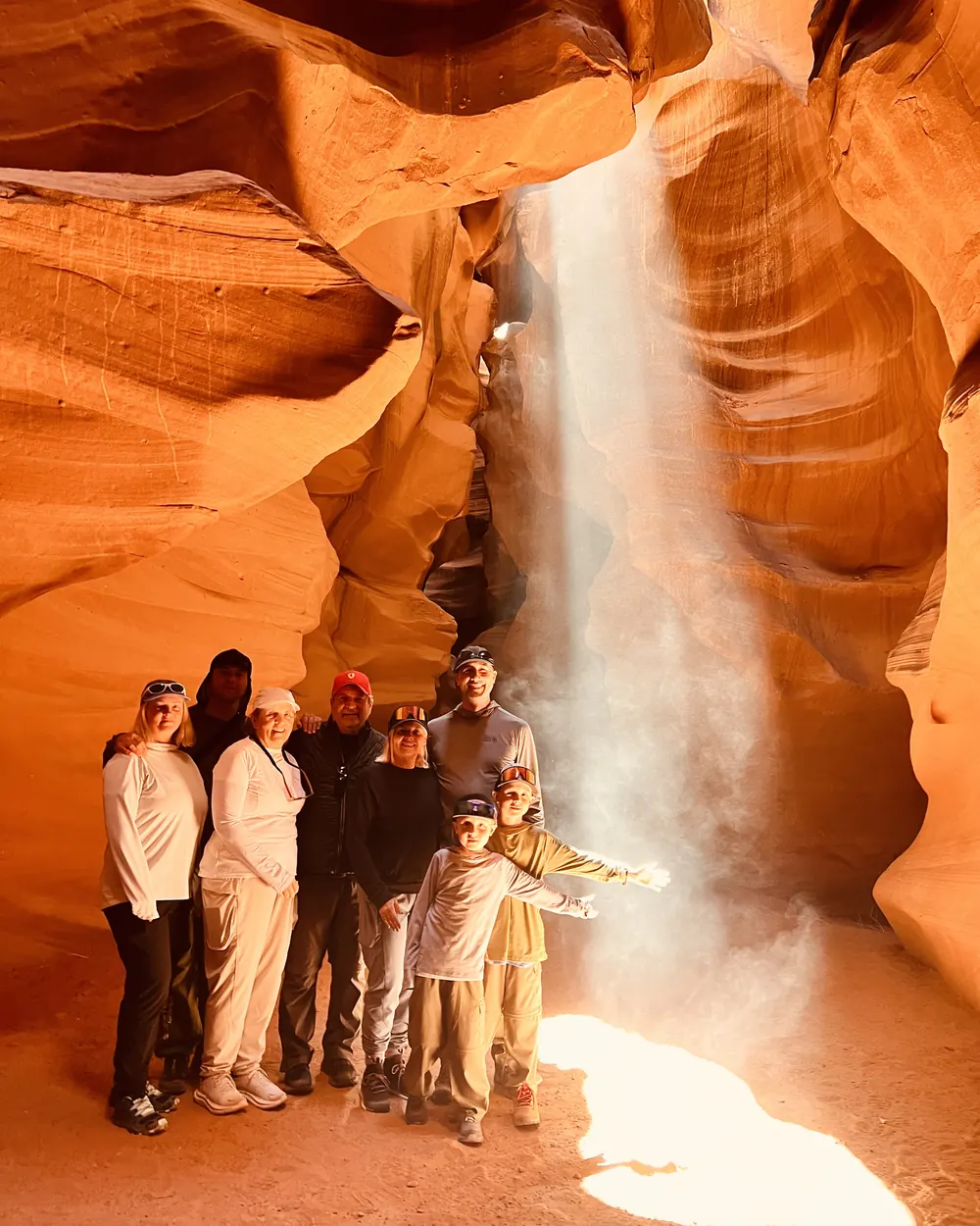 A family in a shaft of sunlight inside Upper Antelope Canyon